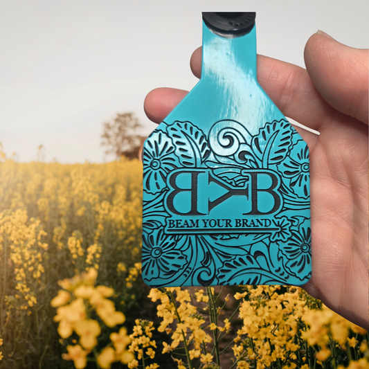 Turquoise Ritchey livestock tag held against a blurred background